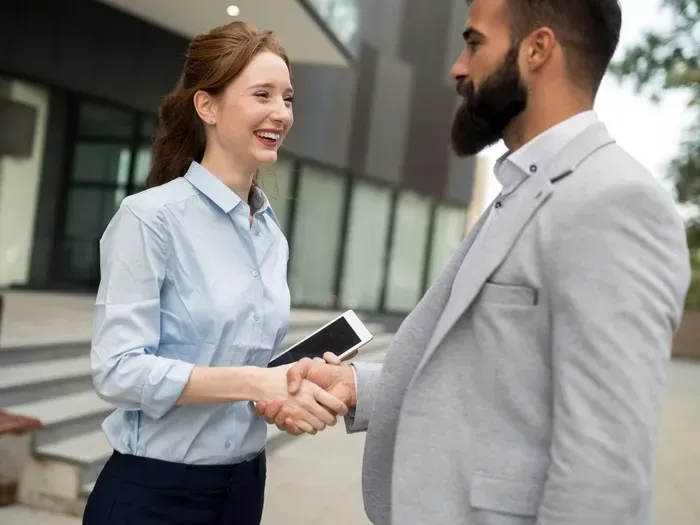 Smiling professionals shake hands outside a building, highlighting listings and partnerships on CityLinkHub